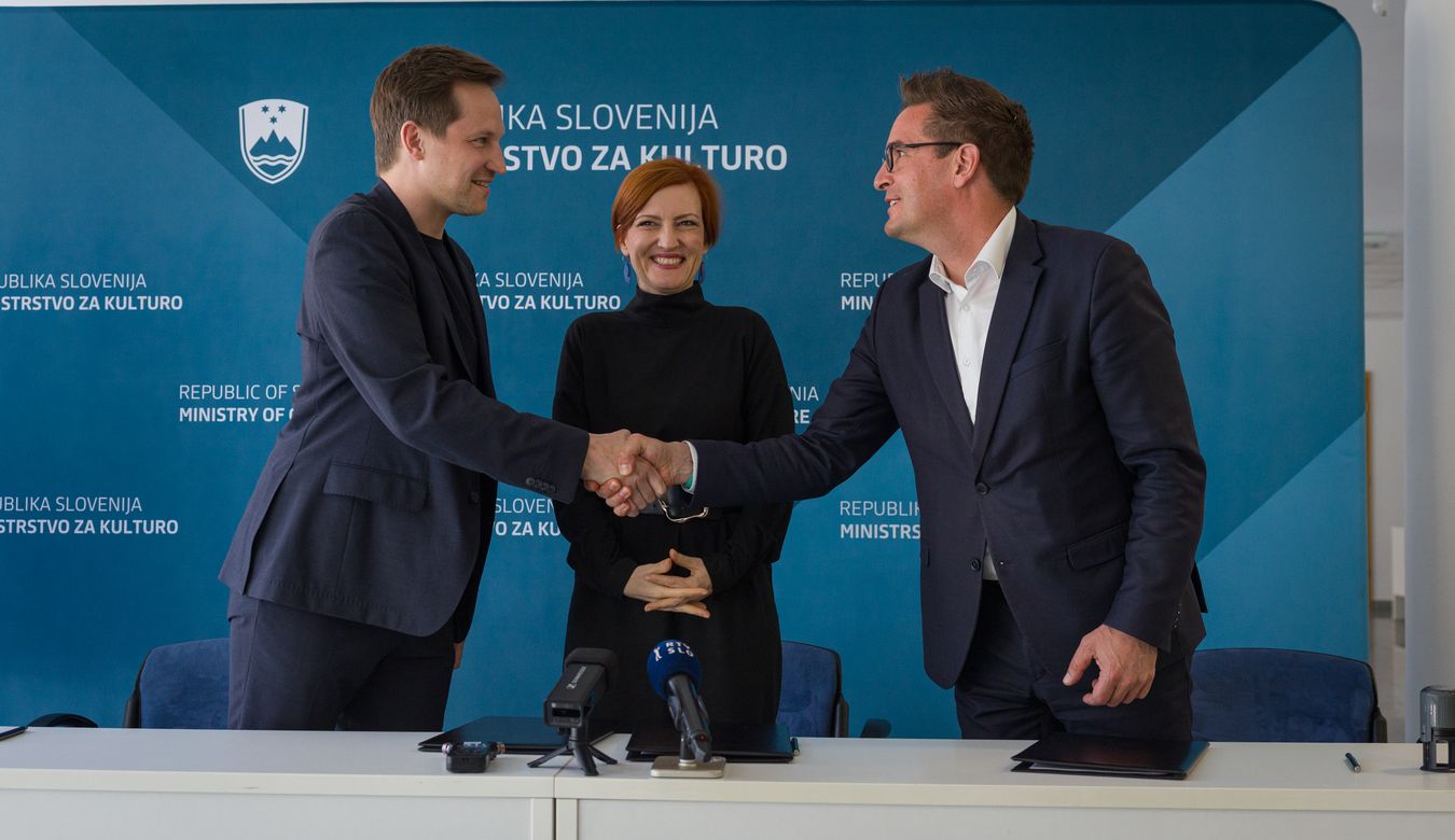 Župan Mestne občine Nova Gorica Samo Turel in župan Mestne občine Celje Matija Kovač, ki se rokujeta po podpisu pogodbe. Zraven je tudi ministrica za kulturo dr. Asta Vrečko