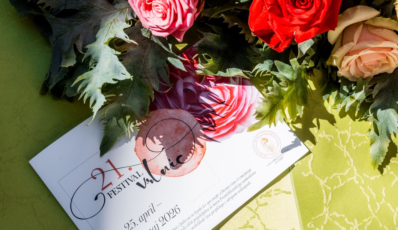 Fotografija zgibanke Festivala vrtnic na mizi, ob aranžmaju vrtnic